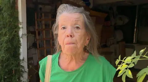 Linda Sheppard at her front door wearing a green t-shirt.