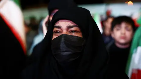 Reuters A woman reacts as people gather after a two-week ceasefire in the Iran war was announced, in Tehran.
