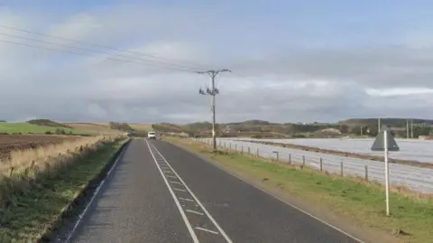 Google A stretch of road near Banff with a van in the distance and fields on either side and a blue sky with a few clouds above