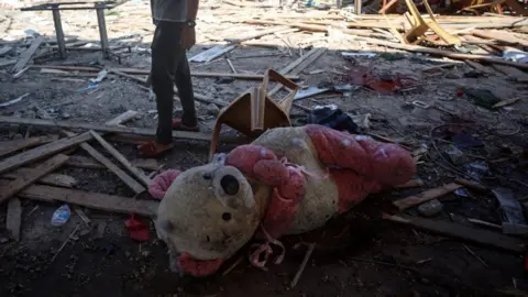 Getty / NurPhoto A pink and white teddy bear lying on the ground among the debris on the floor of the cafe after the strike