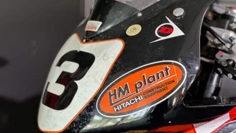 The front on the Superbike that McGuinness rode in the race, which is black and orange with a three on a white plate on the front.