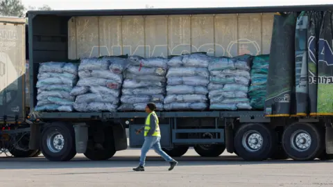 A worker walks near a truck carrying aid at the Kerem Shalom crossing