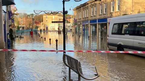Chippenham town centre after flooding from Storm Bert. Bollards along the street can be seen, as well as businesses along either side of the road. They are all closed due to the flood.