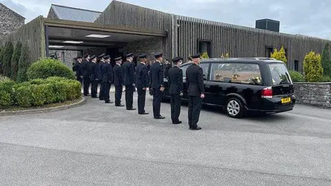 Funeral cortege arriving at a crematorium to a guard of honour