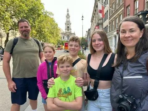 A family smiles and poses for a picture outside Somerset House 