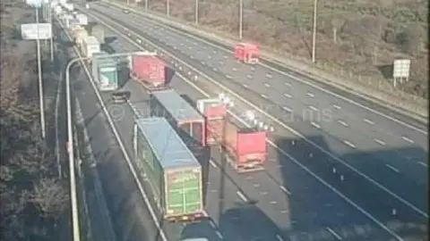 www.motorwaycameras.co.uk Lorries and cars queuing on one side of the motorway. The opposite carriageway is empty, apart from a van and a car