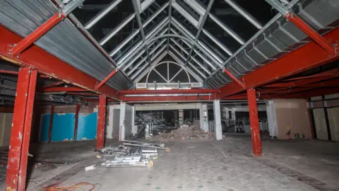 Shrewsbury From Where You Are Not The inside of the glass-roofed entrance to the centre, with rubble and metal rails on the floor