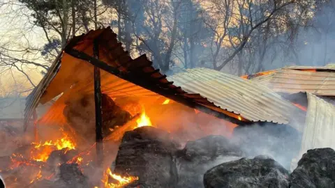 Cleveland Fire Brigade Hay bales placed under a metal outbuilding are on fire. Smoke can be seen rising off the scene.