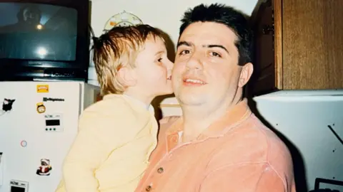 Pancreatic Cancer UK A young boy giving his dad a kiss on the cheek.