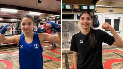 Jaya Kalsi is wearing a blue shirt and is seen in a boxing gym. She is also wearing blue supports on her wrists and is holding both hands aloft. Serena Mali is wearing a black T-shirt, has long hair tied back and is holding a fist in the air. 