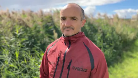 Gareth Clubb de WWF Cymru viste un impermeable rojo y tiene ojos oscuros y cabello corto gris a un lado de la cabeza.