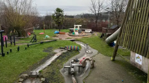 An outdoor play area with a slide and sandpit 