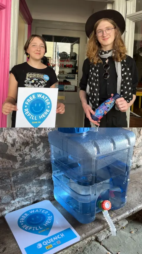 This image has two halves. The top half has a girl on the left and a boy on the right. They are standing in the doorway of a shop. The girl is holding a poster which has a blue water drop symbol with a blue smiley face on it and some words. The words read: 'free water refill here'. The girl has brown hair and is wearing a black t-shirt and earrings. They boy has shoulder length light brown hair. He is wearing a black short sleeved shirt, a black scarf with white stars on, a black hat and glasses. He is holding a multi-coloured metal water bottle. The bottom half of the image shows a large plastic water container with a tap on a wooden bench in the porch of a church. The same poster the girl is holding in the top half of the image is lying flat on the bench alongside the container.