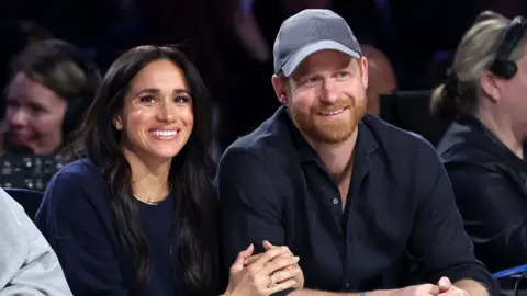 Prince Harry and Meghan sat next to each other and smiling