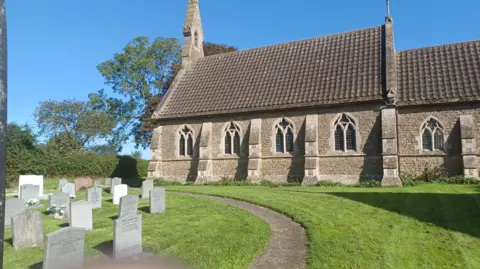 Ian Tomlinson The exterior of a church with some tombstones in the foreground