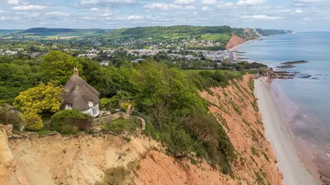Bradleys Estate Agents A second picture looking from above down at the property and the cliff top. It also shows the coastline and sea, to give the full size of the cliff.