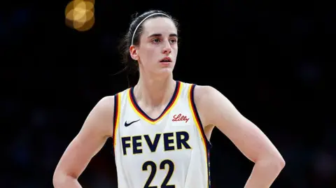 Getty Images Caitlin Clark with her hands on her hips, wearing a jersey for her team