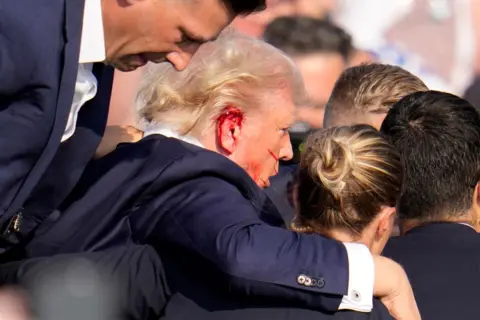 AP Republican presidential candidate former President Donald Trump is helped off the stage at a campaign event in Butler, Pa., on Saturday, July 13, 2024. 