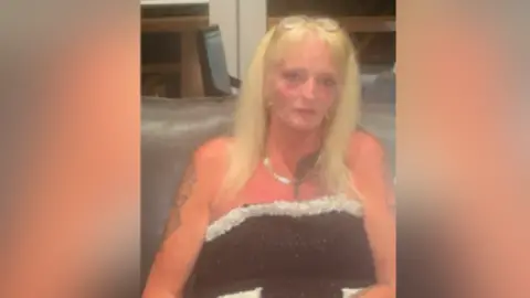 Michelle Maher A blonde woman with long hair wearing a black dress.