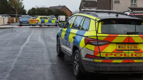 Yellow and blue police vehicle at Breezemount Close in Conlig