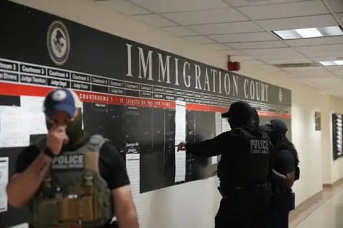 AFP via Getty Images US Immigration and Customs Enforcement (ICE) agents look over lists of names and their hearing times and locations inside the Federal Plaza courthouse before making arrests on 27 June 2025 in New York.