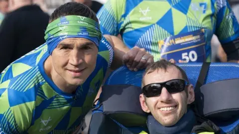 Kevin Sinfield (left), and Rob Burrow, smiling together at the start line of a race, wearing racing clothing.