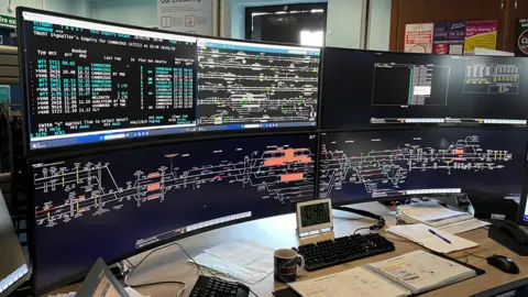 Tom Jackson/BBC A new train signalling system is on four large computer screens which has train routes on it.