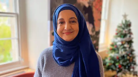 Nasim Patel in a grey jumper and blue hijab. 