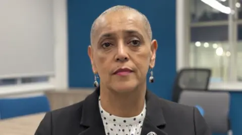 Elizabeth Baines/BBC Alison Lowe, who has shaved hair. She has a neutral expression and is wearing a black blazer.