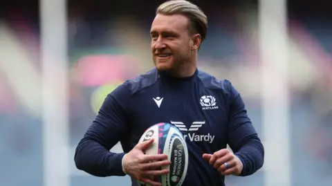 Getty Images Stuart Hogg wearing a blue Scotland kit holding a rugby ball. He has blonde hair which is brushed back.