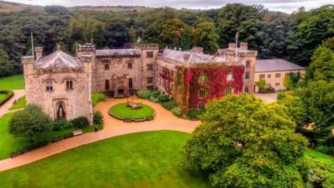 Aerial shot of Towneley Hall in Towneley Park, Burnley surrounded by trees.