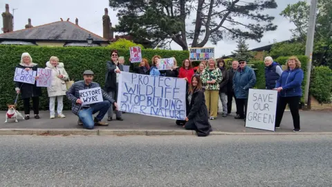 A number of residents in a residential street in Carleton holding signs up opposing the plans for new homes.