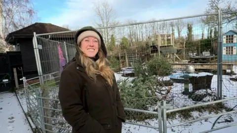 Lizzie standing in front of a snow-covered animal enclosure