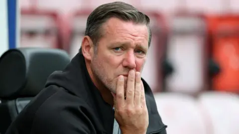 PA Media Kevin Nolan holding his head and looking off camera.