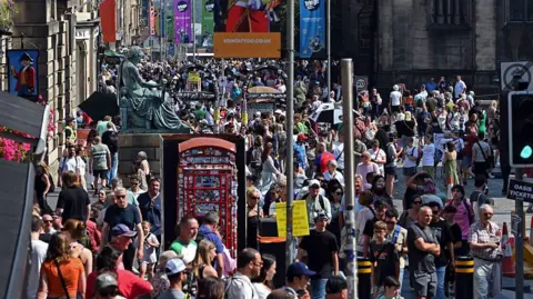 Getty Images Hundreds of people walk along Edinburgh's Royal Mile on a sunny day. 
