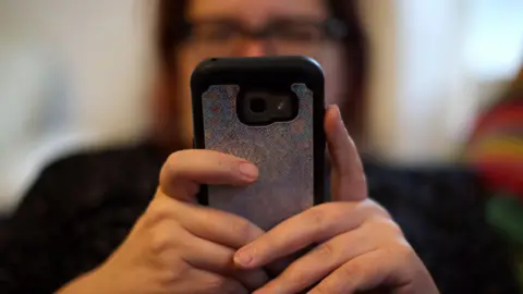 PA Media A woman using her mobile phone