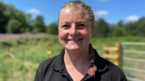 Young woman in black polo neck top pictured in open countryside
