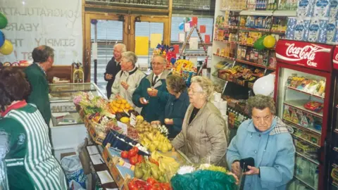 supplied A picture from the 1980'S of a busy fruit and veg store. Customers line up to be served.