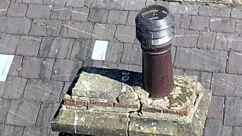 National Lottery Heritage Fund A slate roof with a crumbling chimney stack, taken from above.