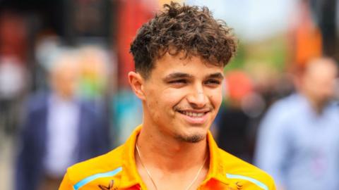 Lando Norris smiles as he arrives in the paddock at Imola 