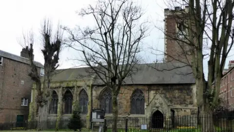 The Grade I listed St Martin-cum-Gregory Church on Micklegate in York, a traditional stone church with a clock tower and trees in the foreground.