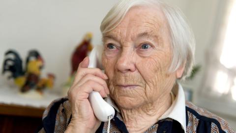 Elderly woman using a landline phone