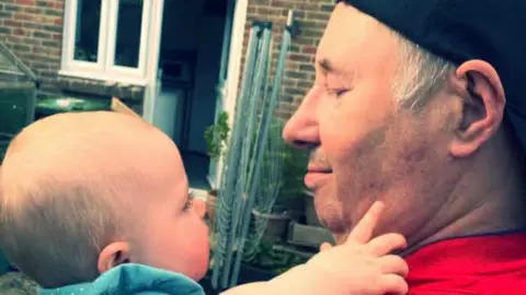 Ian Whitehead Ian Whitehead with one of his baby grandchildren. The pair are both in profile looking at one another. 