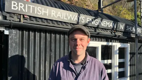 A map with a cap is standing in front of a structure that includes the words British railways engineman.