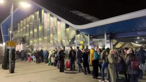 A long queue outside a train station