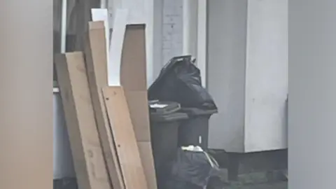 City of Wolverhampton Council A pile of tall cardboard boxes have been piled next to overflowing rubbish bins near a house in Wolverhampton