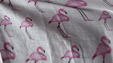 Brian Farmer/BBC A section of a flamingo scarf: white cloth flecked with images of pink flamingos.