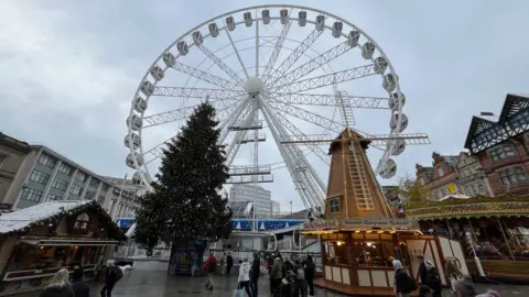 Nottingham Christmas market, with a number of lit stalls selling food, with a ferris wheel towering overhead