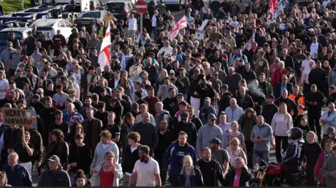 A huge crowd of people, some of whom are wearing St George's flags. 