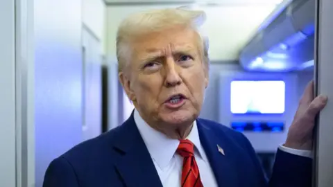 Donald Trump on Air Force One, wearing a blue suit and a red tie.